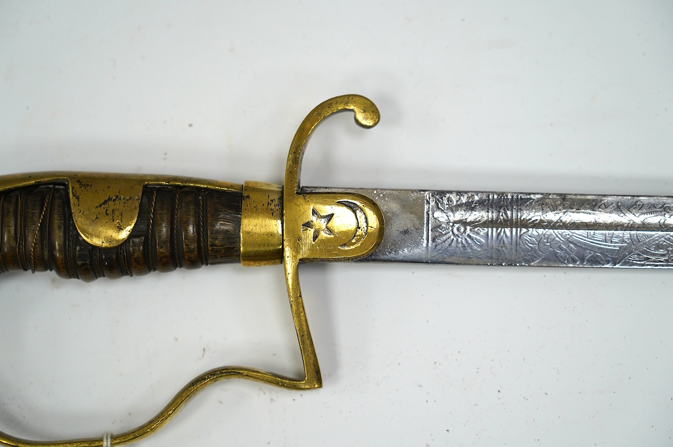 A Turkish WWI artillery sword, etched blade, Vanran Tagirian, Constantinople, brass stirrup hilt and horn grip, blade 70.5cm. Condition - fair, well worn